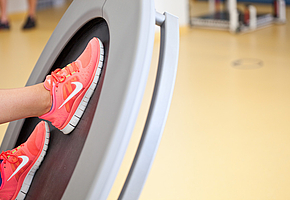 Die Füße einer Frau, die an einem Fitnessgerät trainiert.