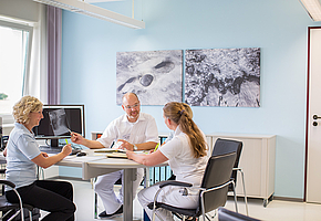 Der Chefarzt der Rehaklinik Sonnhalde bespricht mit drei Angestellten eine Röntgenaufnahme am Computer.