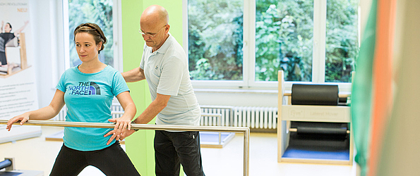 Ein Physiotherapeut hilft einer Patientin bei einer Haltungsübung.