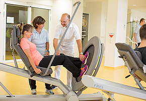 Der Chefarzt der Rehaklinik Sonnhalde hilft einer Patientin bei einer Übung an einem Fitnessgerät.